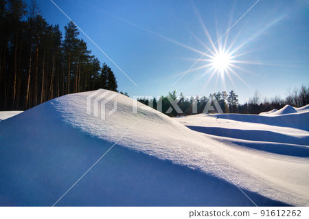 Wonderful winter landscape. Beautiful morning landscape of small snowy hills in winter. Frosty sunny morning. The beauty of winter and the warmth of the sun. 91612262