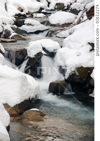 A small active waterfall. Clean mountain stream, snowy winter landscape, wildlife background 91612274