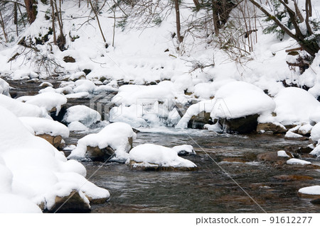 A small active waterfall. Clean mountain stream, snowy winter landscape, wildlife background 91612277