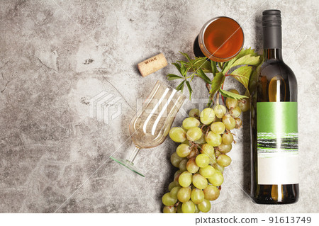 White wine bottle with bunch of grapes, glass on a dark background, top view. White wine bottle with bunch of grapes, glass on a dark background, top view. 91613749