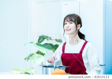 一個穿著圍裙在廚房做飯的女人 91614113