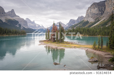 Island of trees in the middle of turquoise alpine lake surrounded by mountains, centered, Canada 91614654