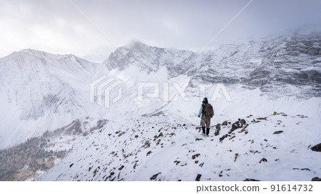 Hiker descending from the mountain during winter, narrow shot, Kananaskis, Canada Hiker descending from the mountain during winter, narrow shot, Kananaskis, Canada 91614732