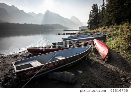 Empty boats lined up on the edge of a lake surrounded by mountains, Jasper NP, Canada 91614766