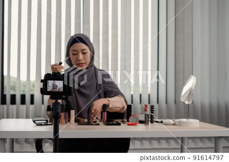 Muslim women making video beauty vlogger bloggers doing a cosmetic makeup tutorial vlog with brushes looking camera Save clips and share them on social media live via the internet Online 91614797