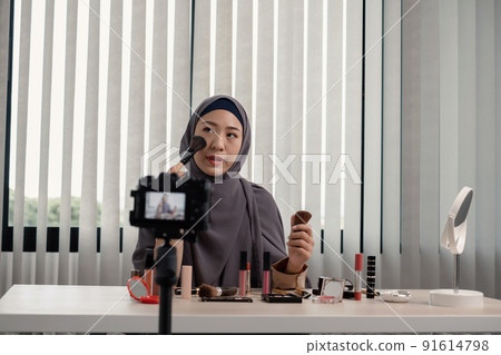 Muslim women making video beauty vlogger bloggers doing a cosmetic makeup tutorial vlog with brushes looking camera Save clips and share them on social media live via the internet Online 91614798