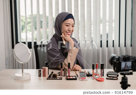 Muslim women making video beauty vlogger bloggers doing a cosmetic makeup tutorial vlog with brushes looking camera Save clips and share them on social media live via the internet Online 91614799