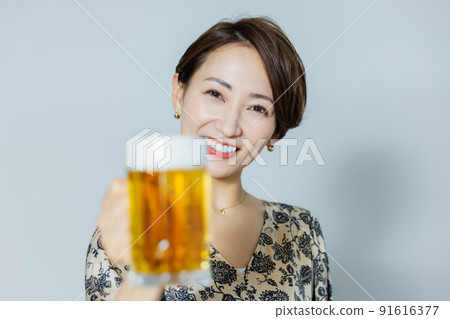 A woman drinking beer with a mug 91616377