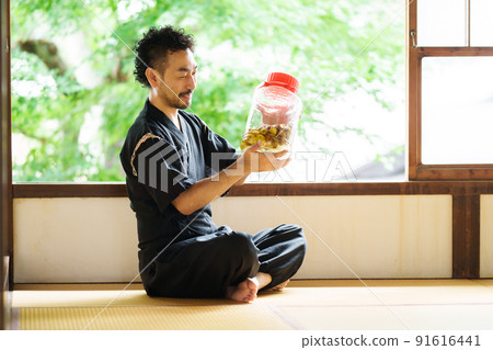 一個大鬍子男人看著釀好的梅酒 91616441