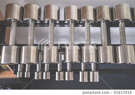 Iron dumbbells on a rack in fitness gym. Sport equipment, simulators. Background. 91617016