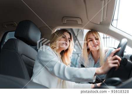 Car dealership consultant showing the interior of the car to a client. 91618328