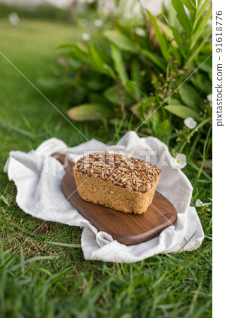 homemade grey bread with seeds on the wood board with the white cloth napkin on the green grass. High quality photo 91618776