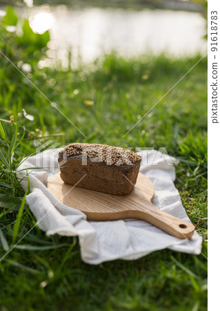 Composition of homemade custard bread on wood board with white cloth napkin on the green grass. High quality photo 91618783