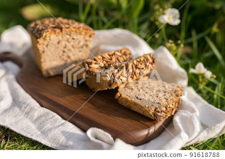 homemade grey bread with seeds on the wood board with the white cloth napkin on the green grass. High quality photo 91618788