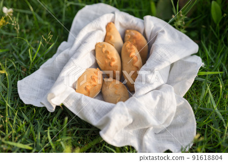 Composition of white flour buns in basket with white white cloth napkin on the green grass. High quality photo 91618804