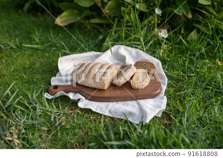 Composition of homemade white flour bread on wood board with white cloth napkin on the green grass . High quality photo 91618808