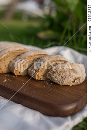 Composition of homemade white flour bread on wood board with white cloth napkin on the green grass . High quality photo 91618815