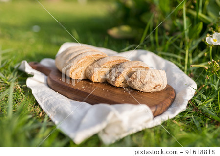 Composition of homemade white flour bread on wood board with white cloth napkin on the green grass . High quality photo 91618818