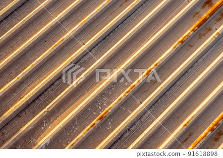Background of rusty old metal panel of the roof of an old factory with diagonal anchor lines. 91618898