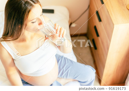 Pregnant drinking water. Young pregnancy mother drink water. Pregnant lady waiting of baby. Glass of water. Concept maternity, childbirth. 91619173