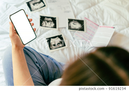 Pregnancy smartphone screen. Pregnant woman holding smartphone mock up. Mobile pregnancy online maternity application. Concept of pregnancy, maternity, expectation for baby birth. Pregnancy smartphone screen. Pregnant woman holding smartphone mock up. Mobile pregnancy online maternity application. Concept of pregnancy, maternity, expectation for baby birth. 91619234