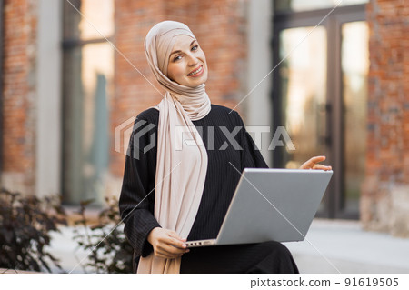 Elegant, tall, slim and wearing black clothes and turban, smiling while working during break. Elegant, tall, slim and wearing black clothes and turban, smiling while working during break. 91619505