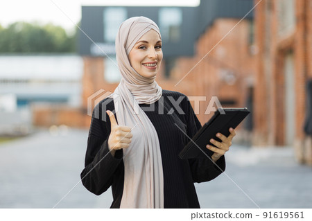 Happy arabic girl standing outdoor and checking email on digital gadget. Happy arabic girl standing outdoor and checking email on digital gadget. 91619561