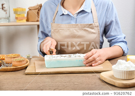 Woman cutting natural handmade soap on wooden table, closeup Woman cutting natural handmade soap on wooden table, closeup 91620762