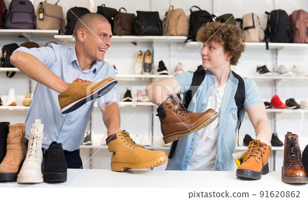 Cheerful man and teenage boy having fun in shoe store Cheerful man and teenage boy having fun in shoe store 91620862
