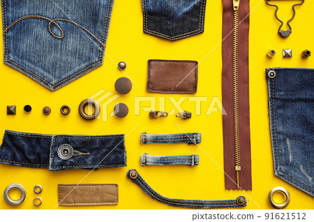 Flat lay composition with garment accessories and cutting details for jeans on yellow background 91621512