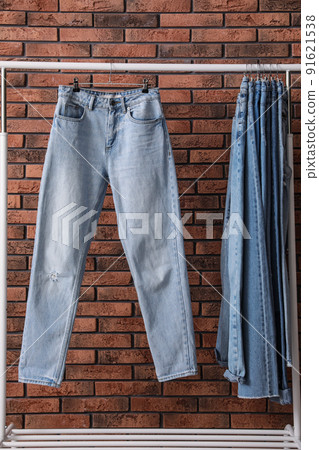 Rack with stylish jeans near brick wall Rack with stylish jeans near brick wall 91621538