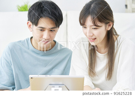 一對夫婦在客廳裡看平板電腦 91625228