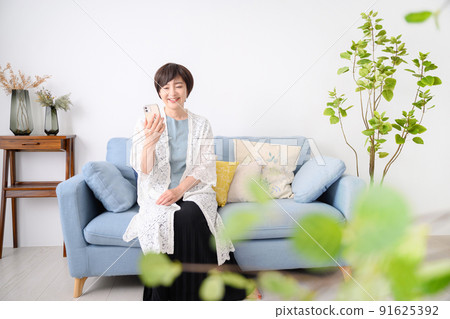 Smiling woman looking at smartphone 91625392