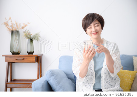 Smiling woman looking at smartphone 91625393