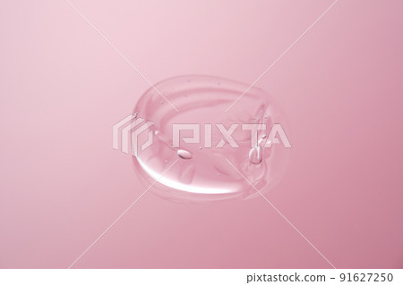 Drop of cosmetic transparent gel on a pink background. The texture of the serum, heir gel or hyaluronic booster. Drop of cosmetic transparent gel on a pink background. The texture of the serum, heir gel or hyaluronic booster. 91627250