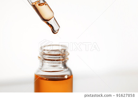 Pipette with orange fluid hyaluronic acid or serum. Cosmetics, science and healthcare concept closeup. Dose of serum or retinol falls in a bottle. Front view. Beauty product presentation, macro Pipette with orange fluid hyaluronic acid or serum. Cosmetics, science and healthcare concept closeup. Dose of serum or retinol falls in a bottle. Front view. Beauty product presentation, macro 91627858