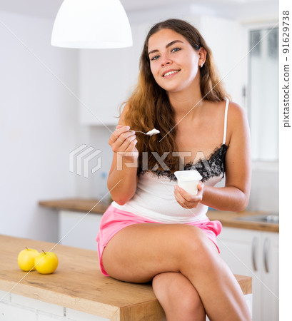 Portrait of positive girl eating yogurt at home 91629738