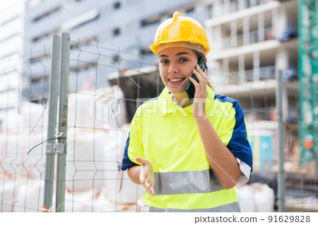 Woman architect talking by phone at building site 91629828