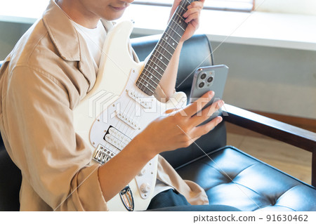 A young man playing a white electric guitar (smartphone) 91630462