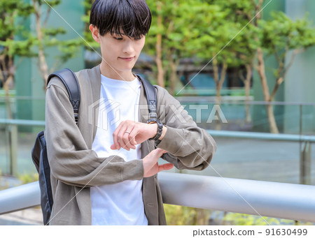 Office casual young businessman checking time with a wristwatch Office casual young businessman checking time with a wristwatch 91630499