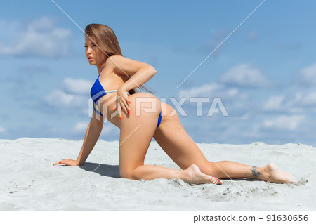 Graceful woman in bikini on sandy beach Graceful woman in bikini on sandy beach 91630656