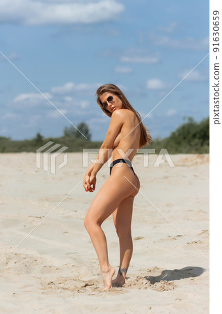 Alluring woman covering breast on beach 91630659