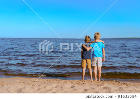 boys standing on beach lookind at horizon over Ladoga lake, Russia 91632584