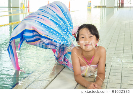 一個可愛的小學女孩在溫水游泳池裡練習美人魚 一個可愛的小學女孩在溫水游泳池裡練習美人魚 91632585