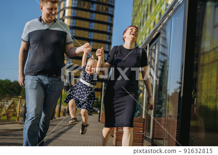 Happy caucasian family couple enjoy walking with daughter. mother happily laughing Happy caucasian family couple enjoy walking with daughter. mother happily laughing 91632815