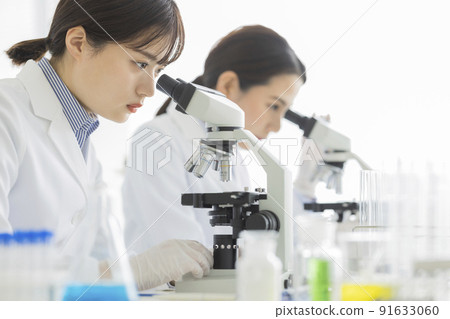 一個穿白大褂的女人透過顯微鏡看 一個穿白大褂的女人透過顯微鏡看 91633060