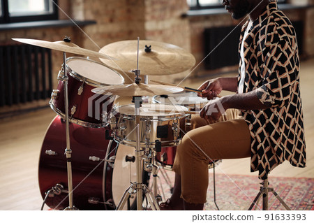 African musician playing at drums set with drumsticks at empty studio African musician playing at drums set with drumsticks at empty studio 91633393