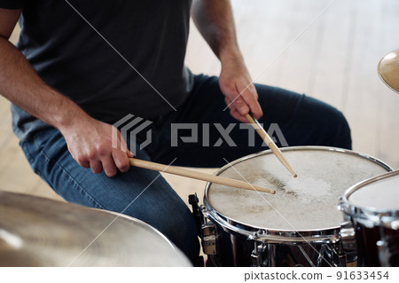 Close-up of young drummer beating with drumsticks on drums during playing song Close-up of young drummer beating with drumsticks on drums during playing song 91633454