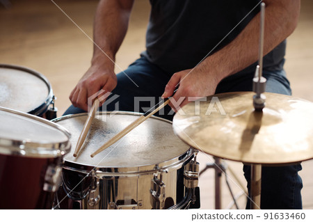 Close-up of man sitting behind drum kit and playing drums during rehearsal 91633460