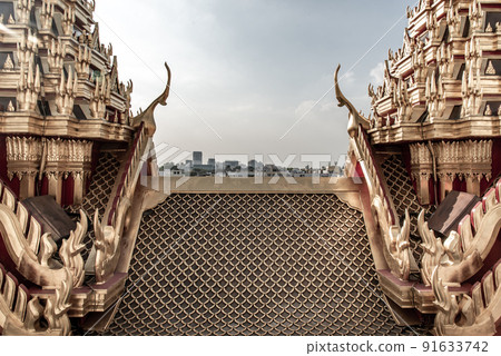 Symmetry view of Loha Prasart Metal Palace at Ratchanaddaram temple beyond the golden temple roof. 91633742